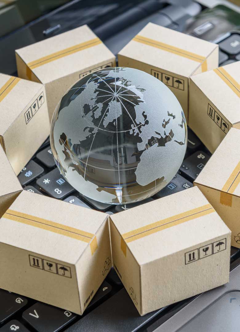 Glass globe with cardboard shipping boxes on top of a laptop keyboard